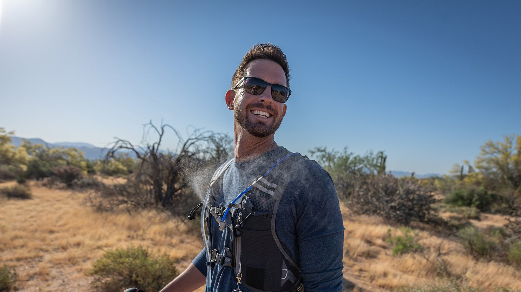 hiker in desert wearing misting hydration backpack on sunny day in hot weather