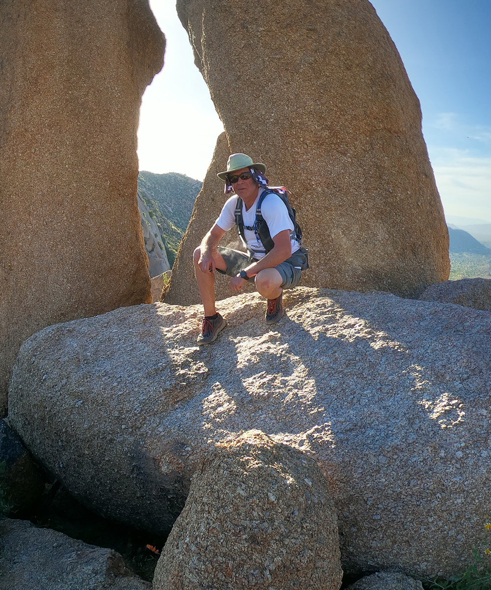 ron hiking on boulders in hot weather wearing misting hydration backpack