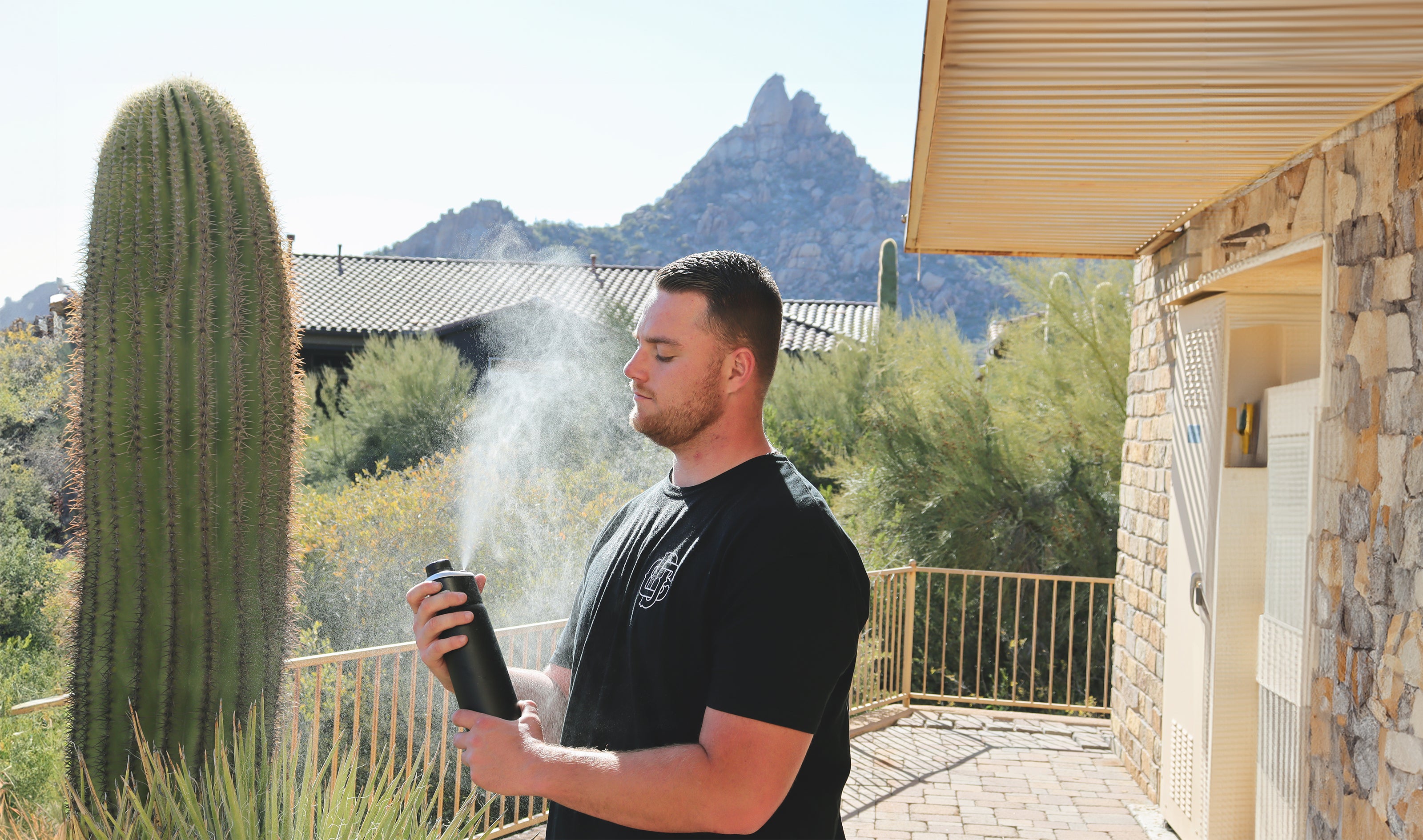 Man holding a misting water bottle outdoors on hot day