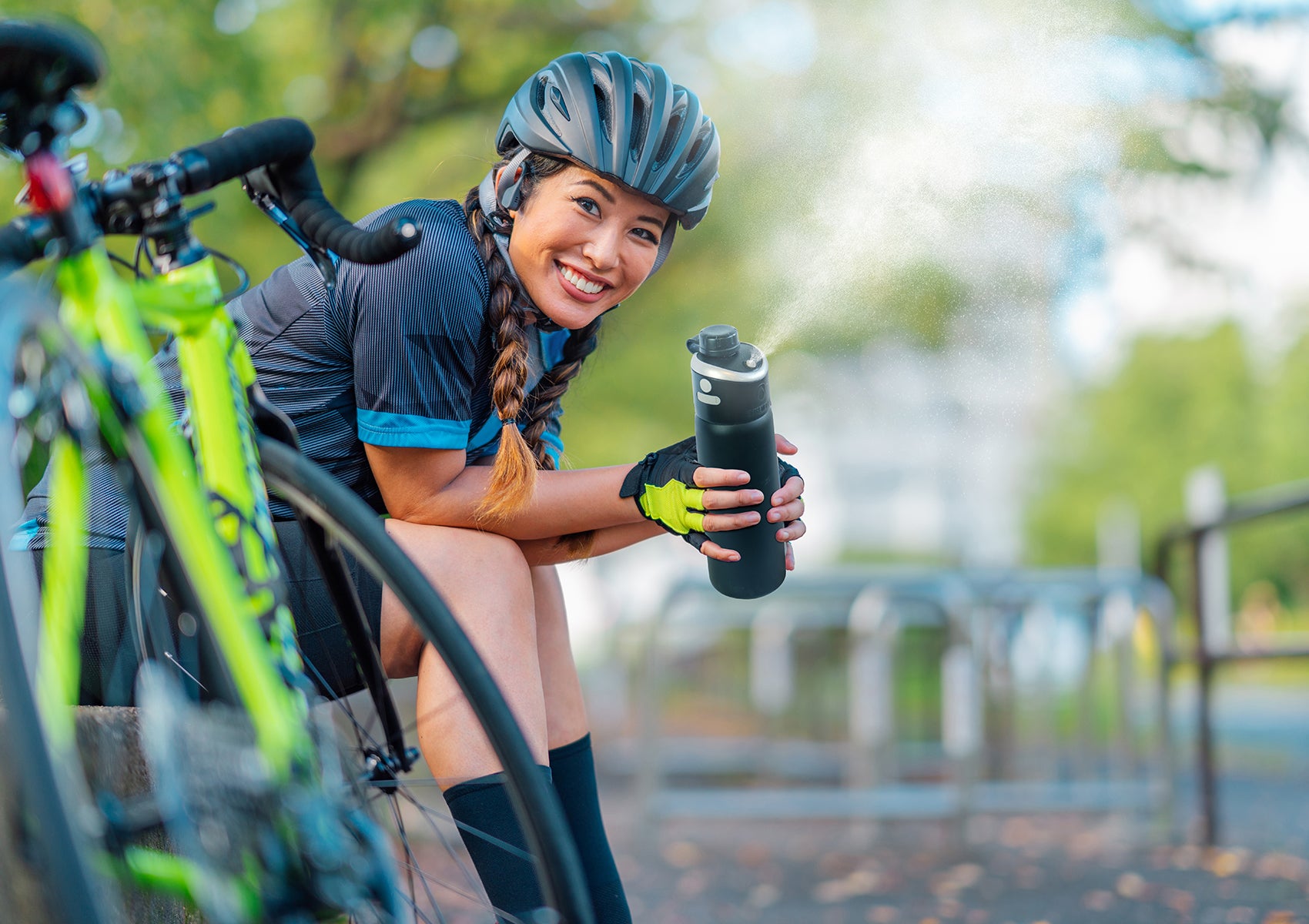 biking woman using misting water bottle to cool herself off outside in hot weather