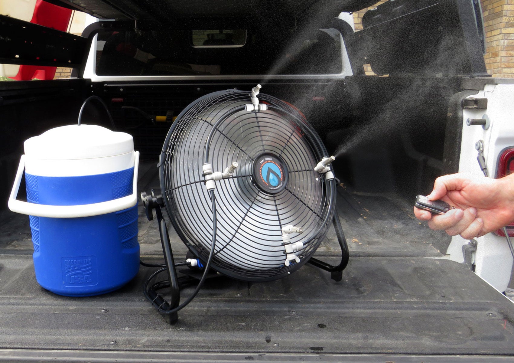 portable misting with 4 nozzles spraying mist in bed of truck with water cooler and wireless remote
