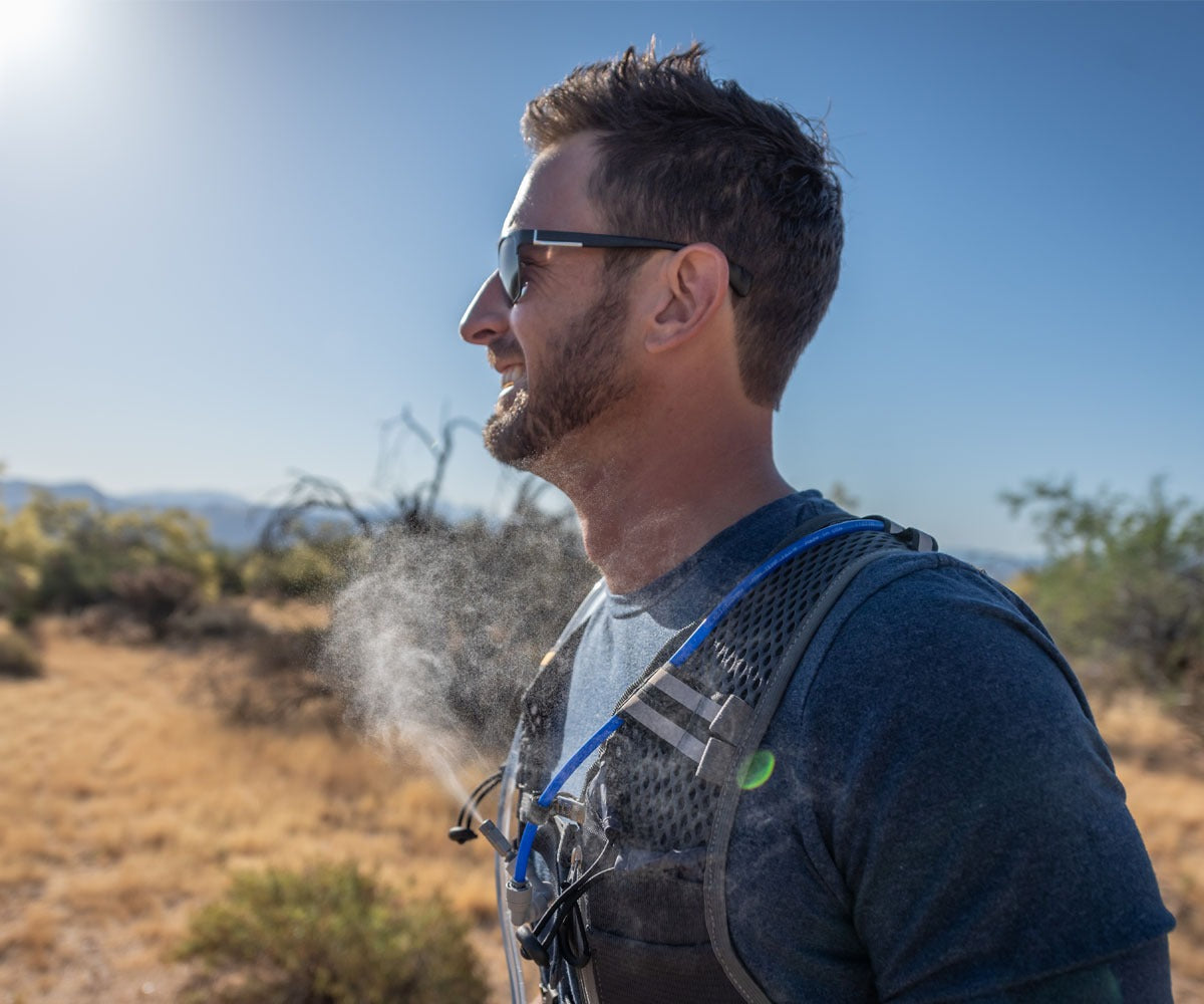 hiker wearing sunglasses in hot weather wearing misting hydration backpack